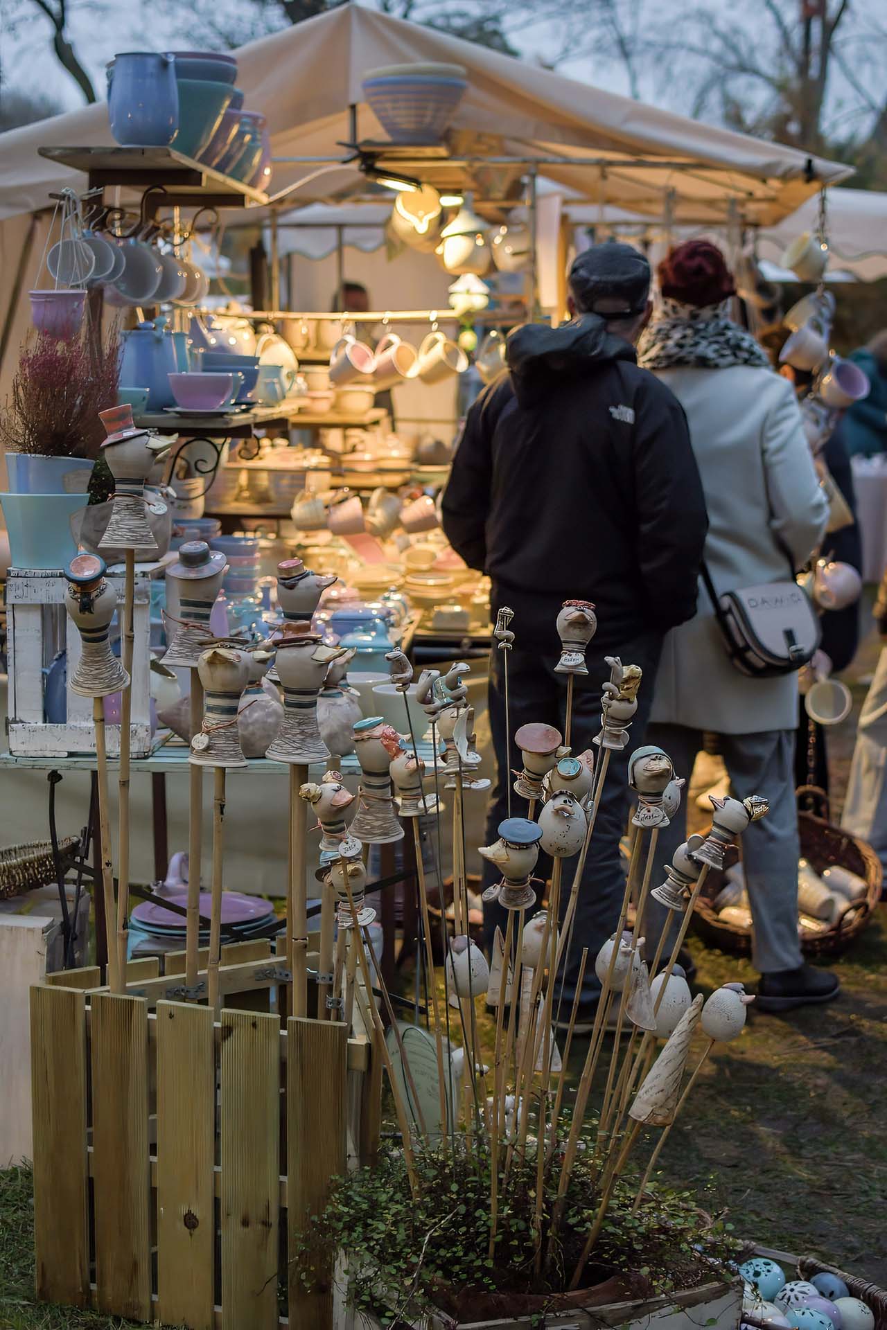 Warm beleuchtete Marktstände mit Keramik am Abend.