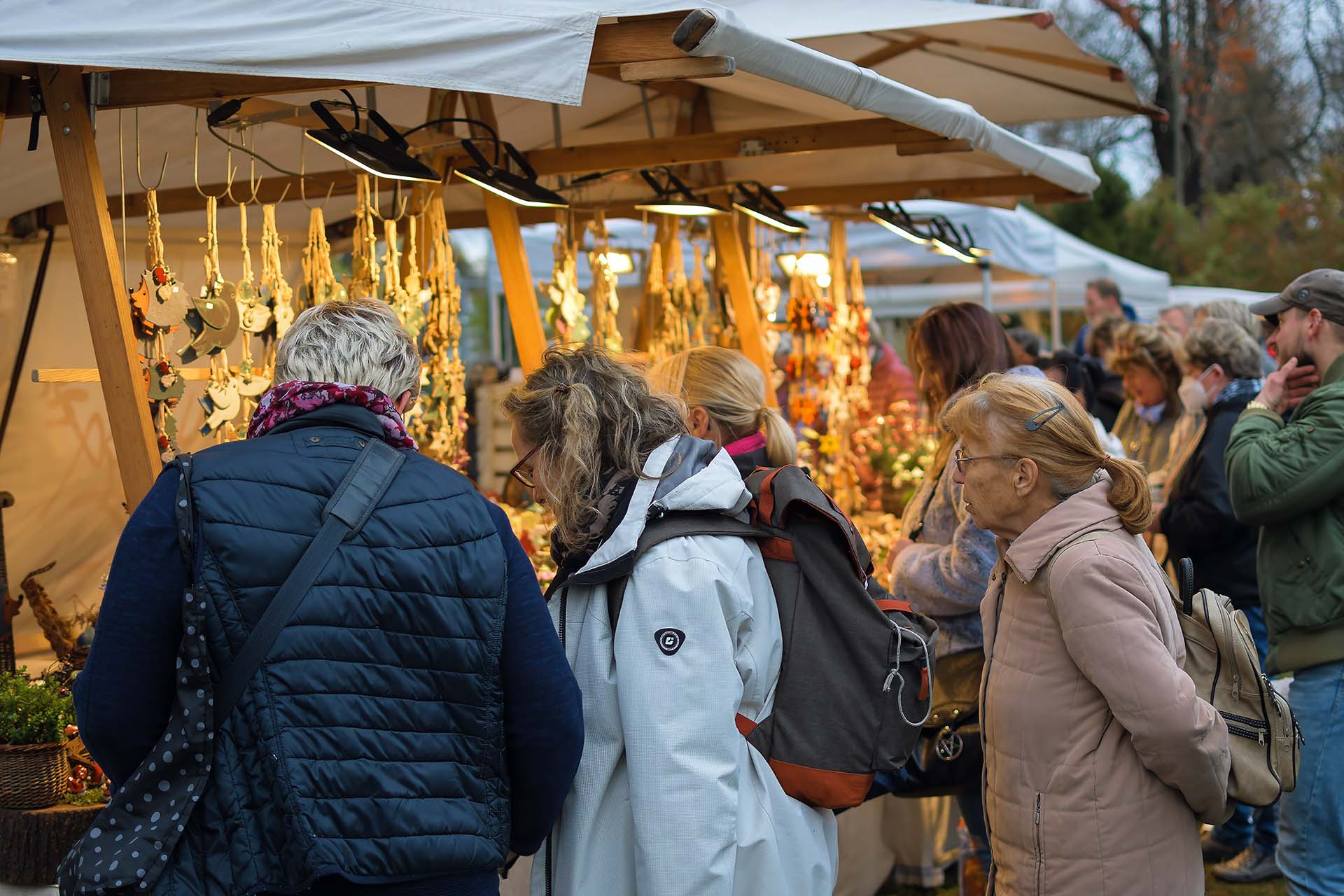 Besucher betrachten hängende Keramik-Anhänger an einem Stand.